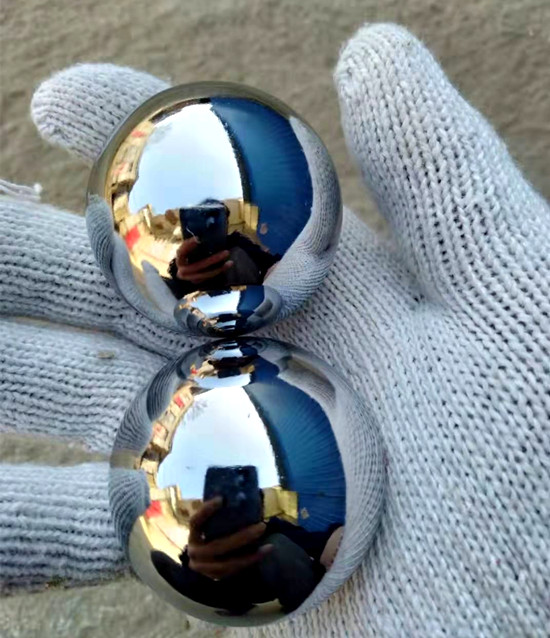 Hand with glove holding two chrome baoding balls