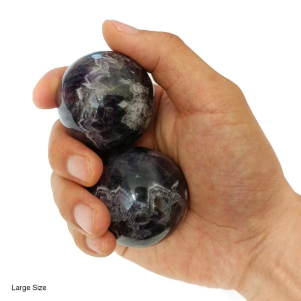 Hand holding large amethyst baoding balls