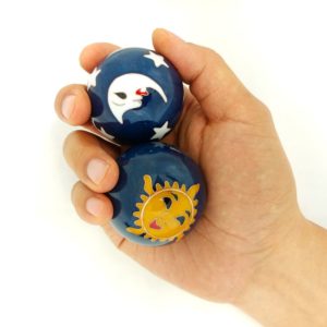 Hand holding large sun and moon baoding balls.