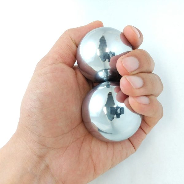 Hand holding two large chrome baoding balls