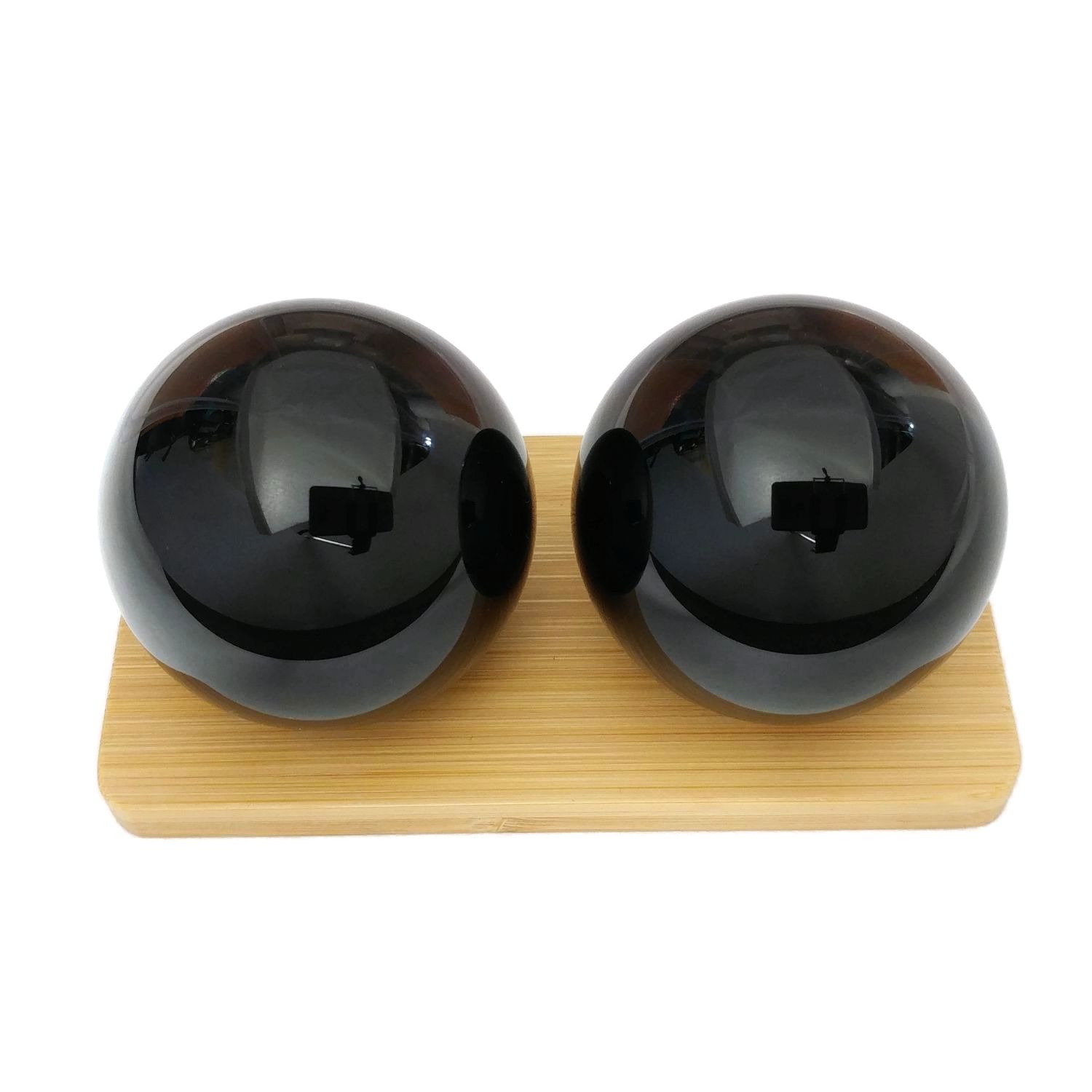 Black obsidian baoding balls on a bamboo display stand