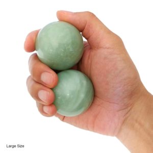 Hand holding large green jade baoding balls