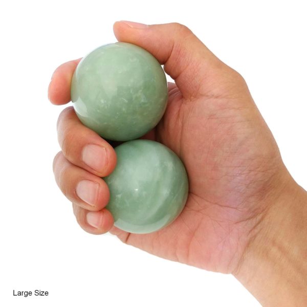 Hand holding large green jade baoding balls
