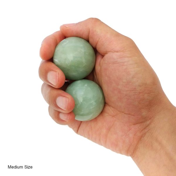 Hand holding medium green jade baoding balls