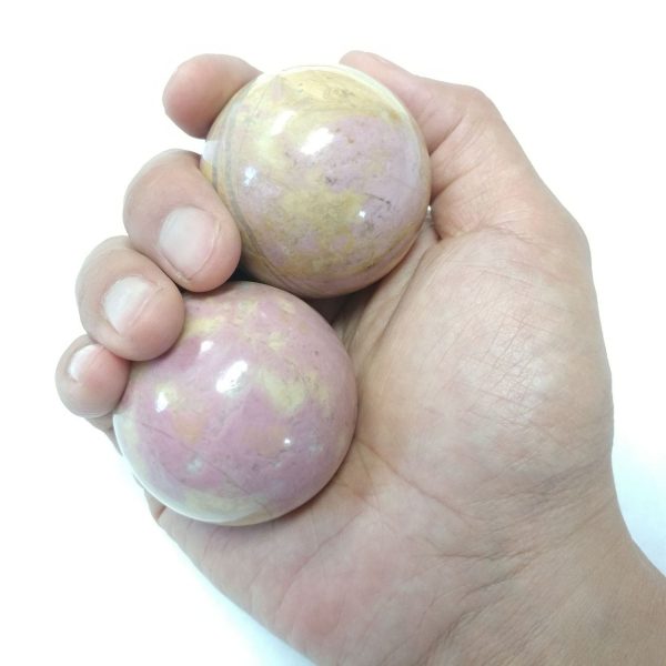 Hand holding large rhodonite baoding balls
