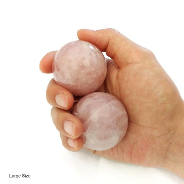 Hand holding large rose quartz baoding balls