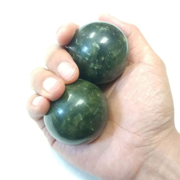 Hand holding large xiuyan jade baoding balls