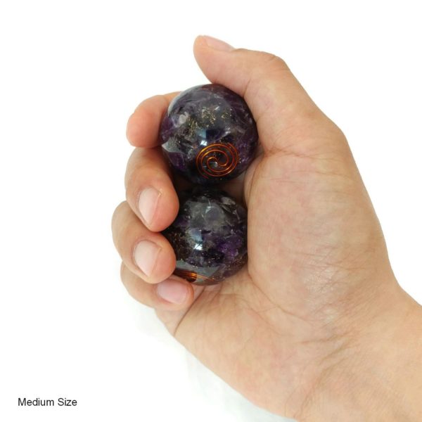 Hand holding amethyst orgonite baoding balls