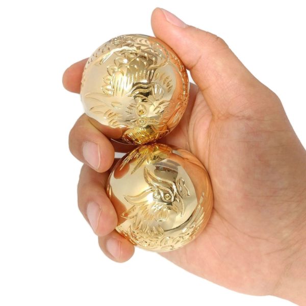 Hand holding golden carved dragon and phoenix baoding balls